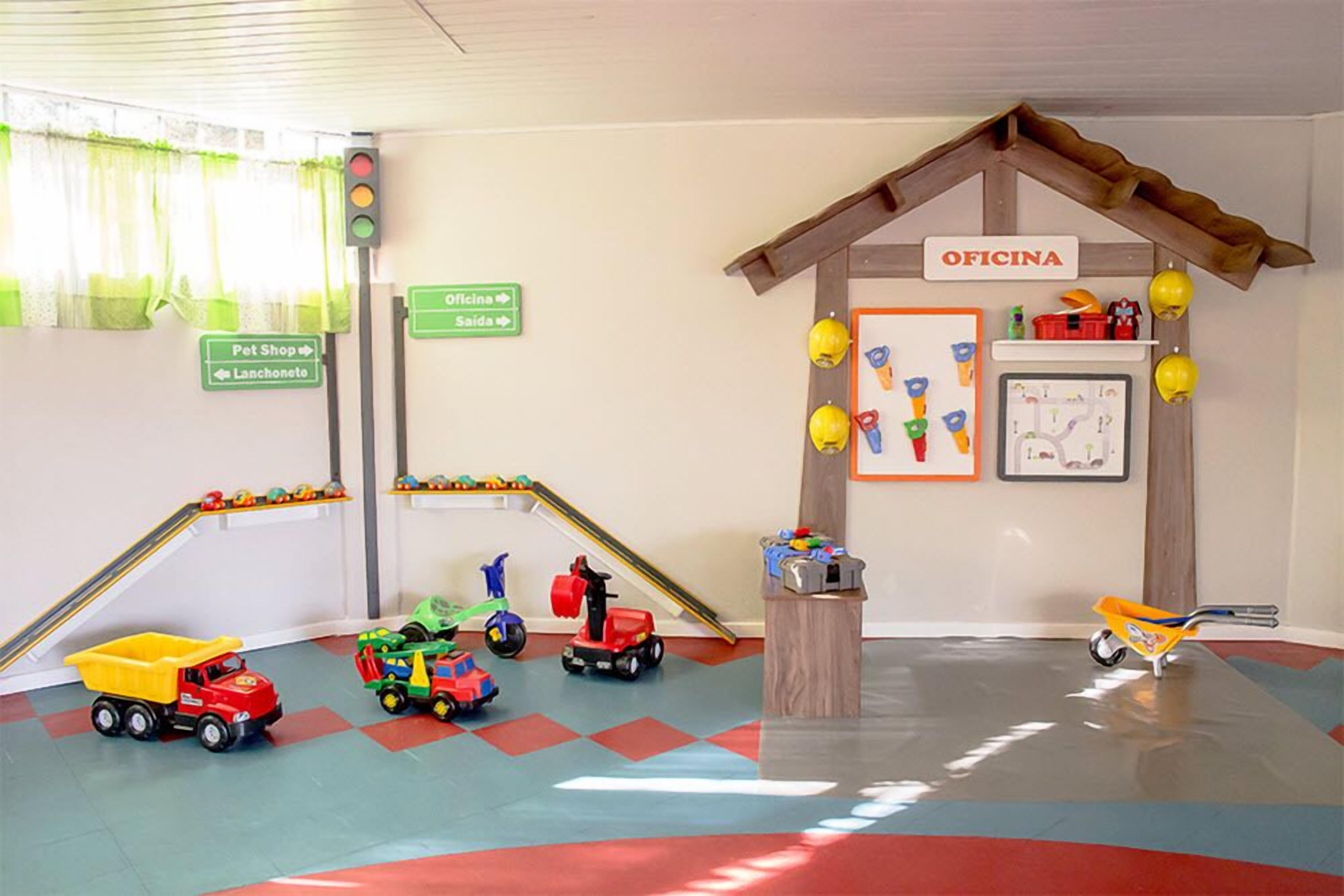 Zona de jocs amb vehicles de joc, semàfor i indicadors de direcció cap a la botiga de mascotes i l'oficina.
