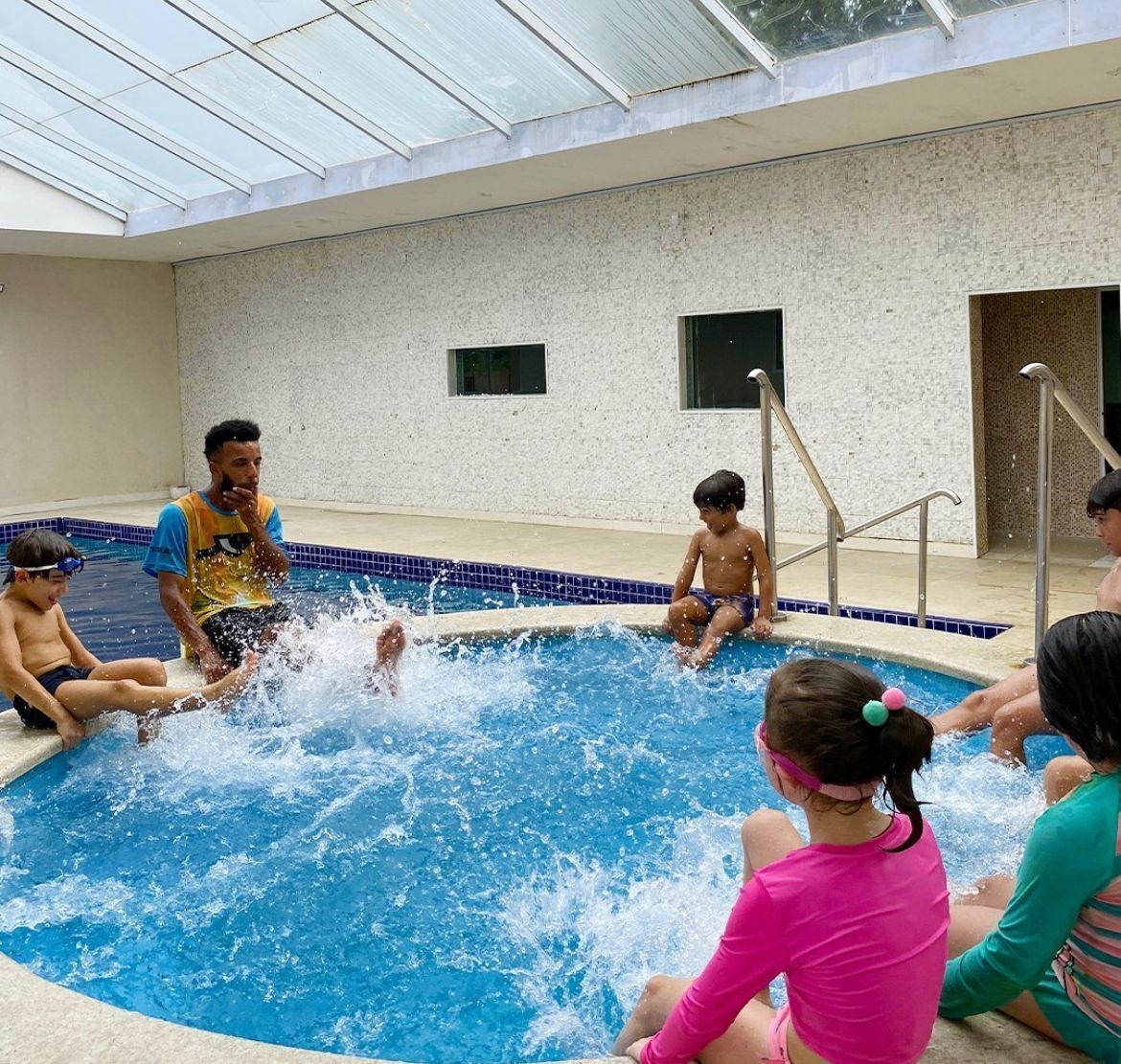 An indoor swimming pool with a glass ceiling, tiled walls, and a clear view of the sky.
