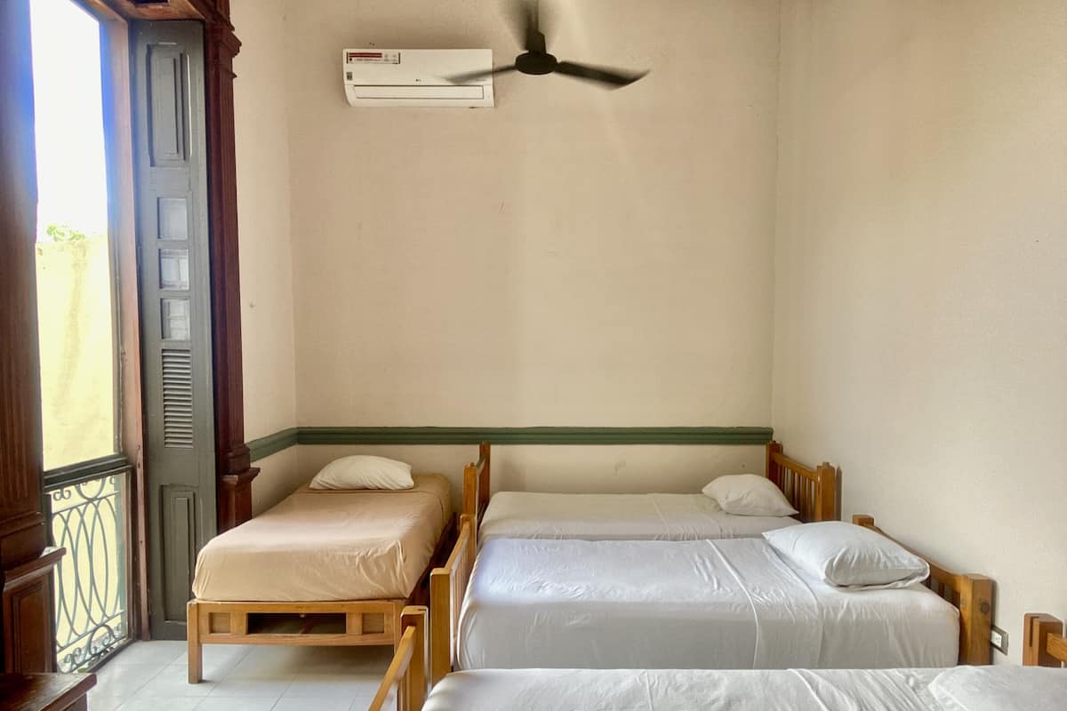 Ein Zimmer mit zwei Holzbetten, einem Deckenventilator und einer Klimaanlage.