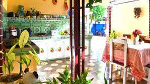 A kitchen with green cabinets, a dining area with a table and chairs, and a tiled floor. - Hostal la Campiña (Remedios)