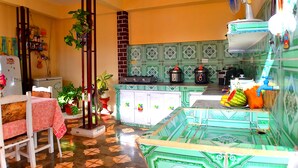 A kitchen with a tiled backsplash, a refrigerator, a sink, and a dining area with a table and chairs. - Hostal la Campiña (Remedios)