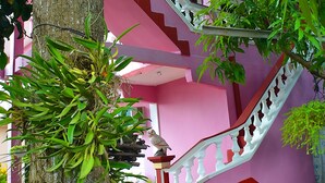 A staircase with pink walls and white balustrades, surrounded by greenery and potted plants. - Hostal la Campiña (Remedios)