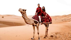 A camel with a rider and a passenger in a desert.