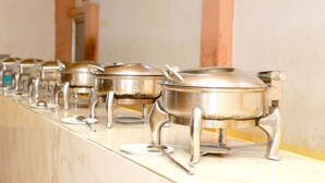 A row of stainless steel pots on a marble countertop in a kitchen.