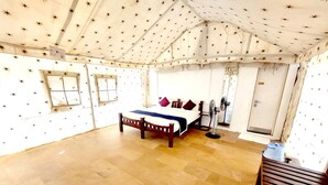 A tented room with a bed, a bench, and a small table.
