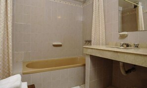 A bathroom with a bathtub, a sink, and a mirror.