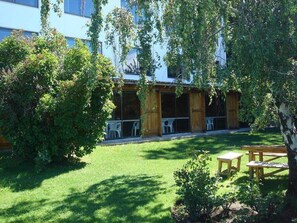 A courtyard with a wooden pergola, outdoor seating, and a building in the background.
