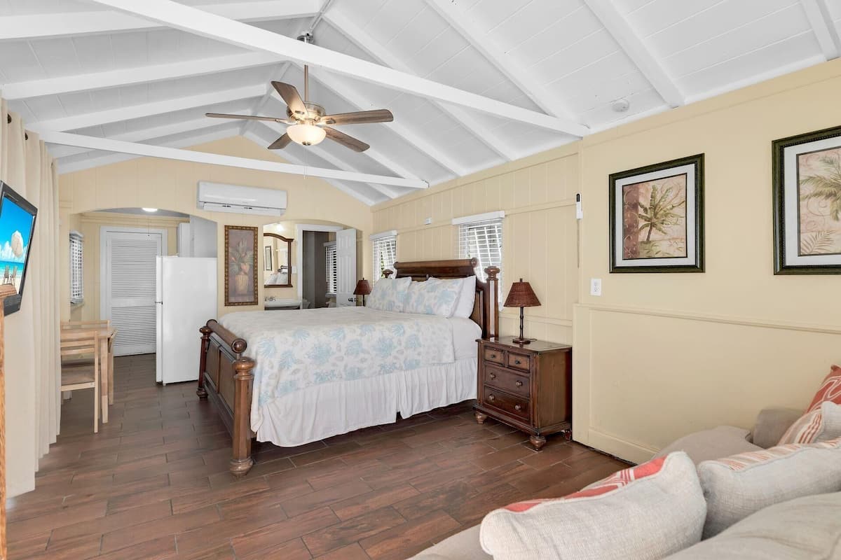 A bedroom with a bed, a ceiling fan, a dresser, and a nightstand.