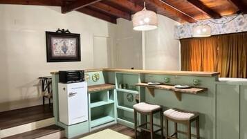 A compact kitchen with a wooden ceiling, a white refrigerator, and a small island with stools.