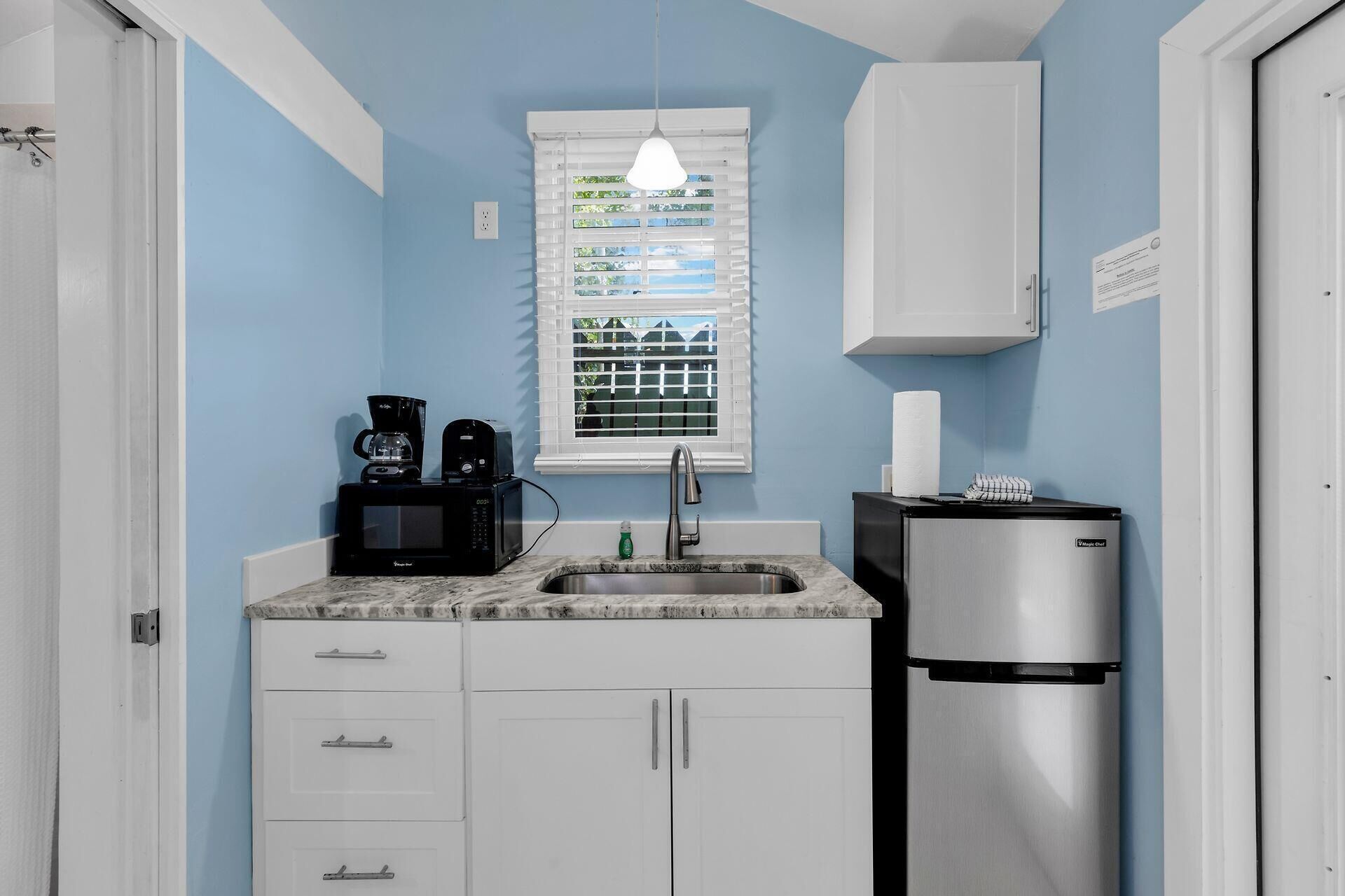 A compact kitchen with a microwave, coffee maker, sink, and refrigerator.