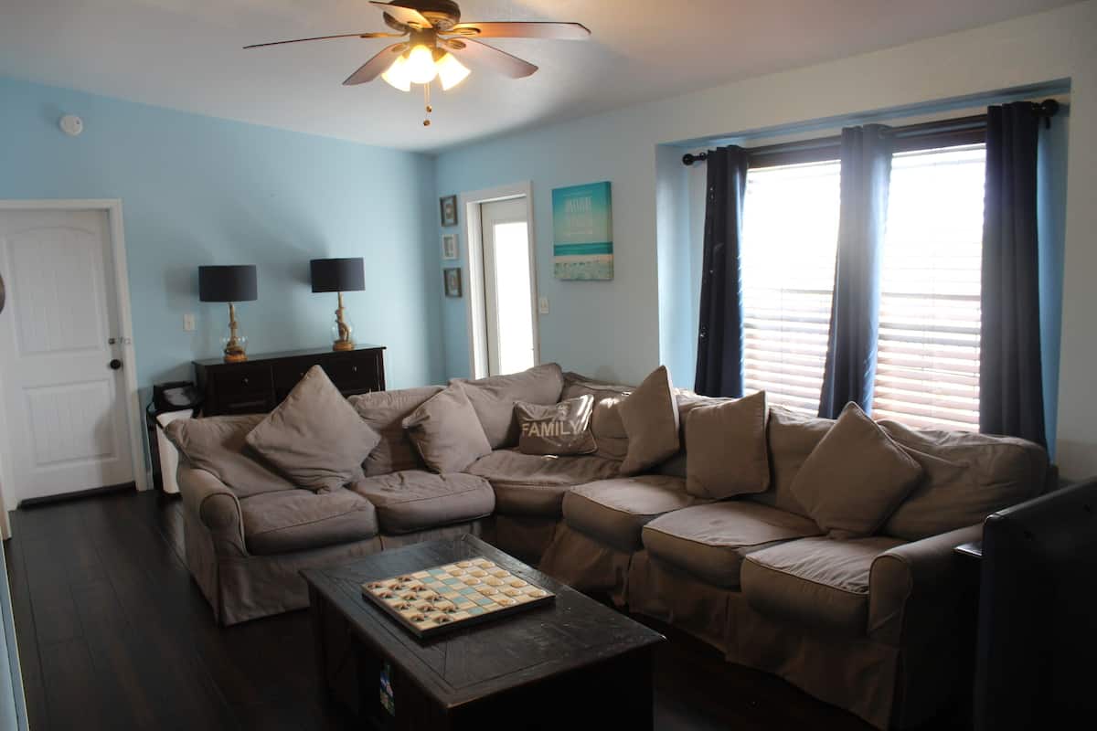 A living room with a sectional sofa, a coffee table, and a ceiling fan.