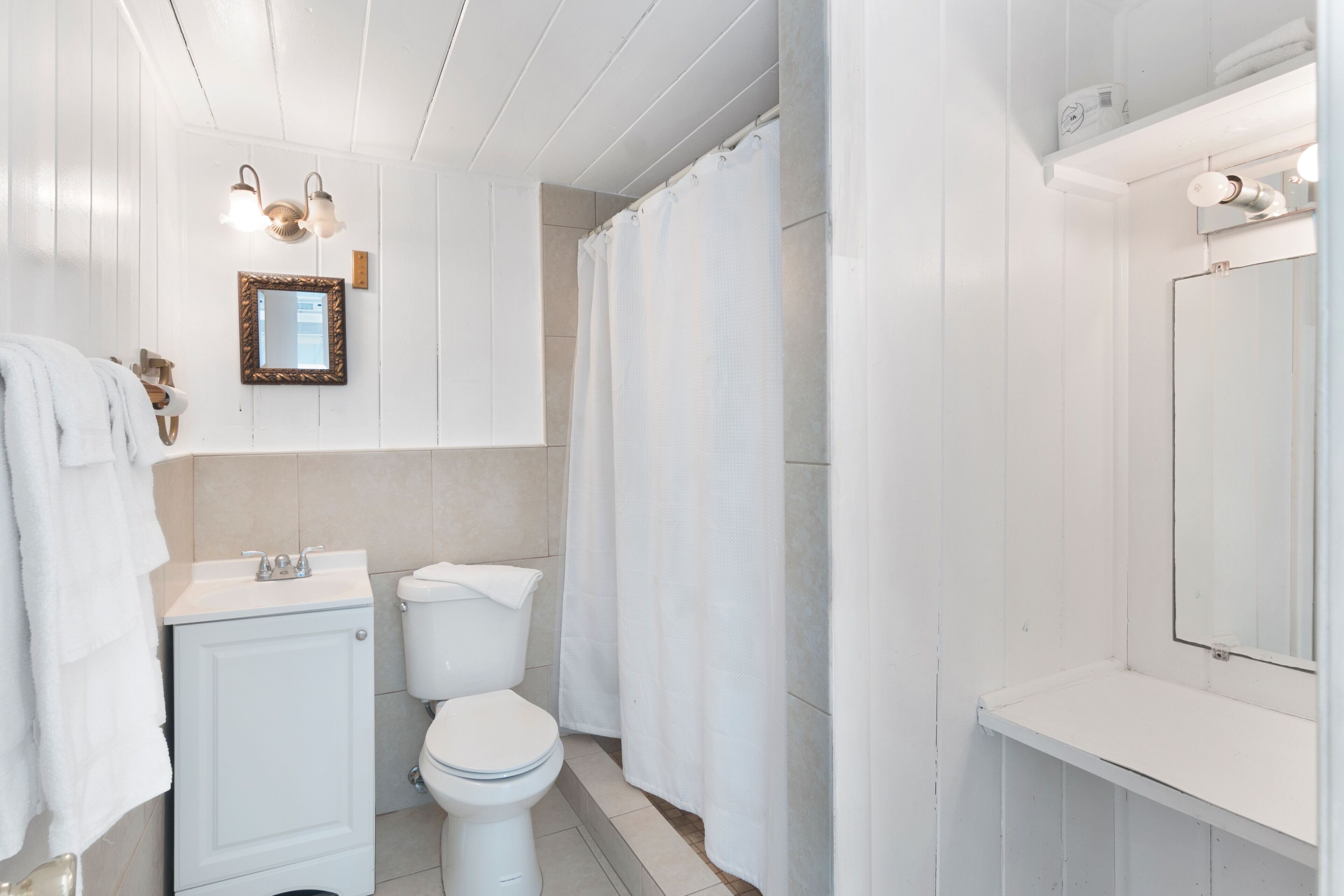 A bathroom with a toilet, sink, and mirror.