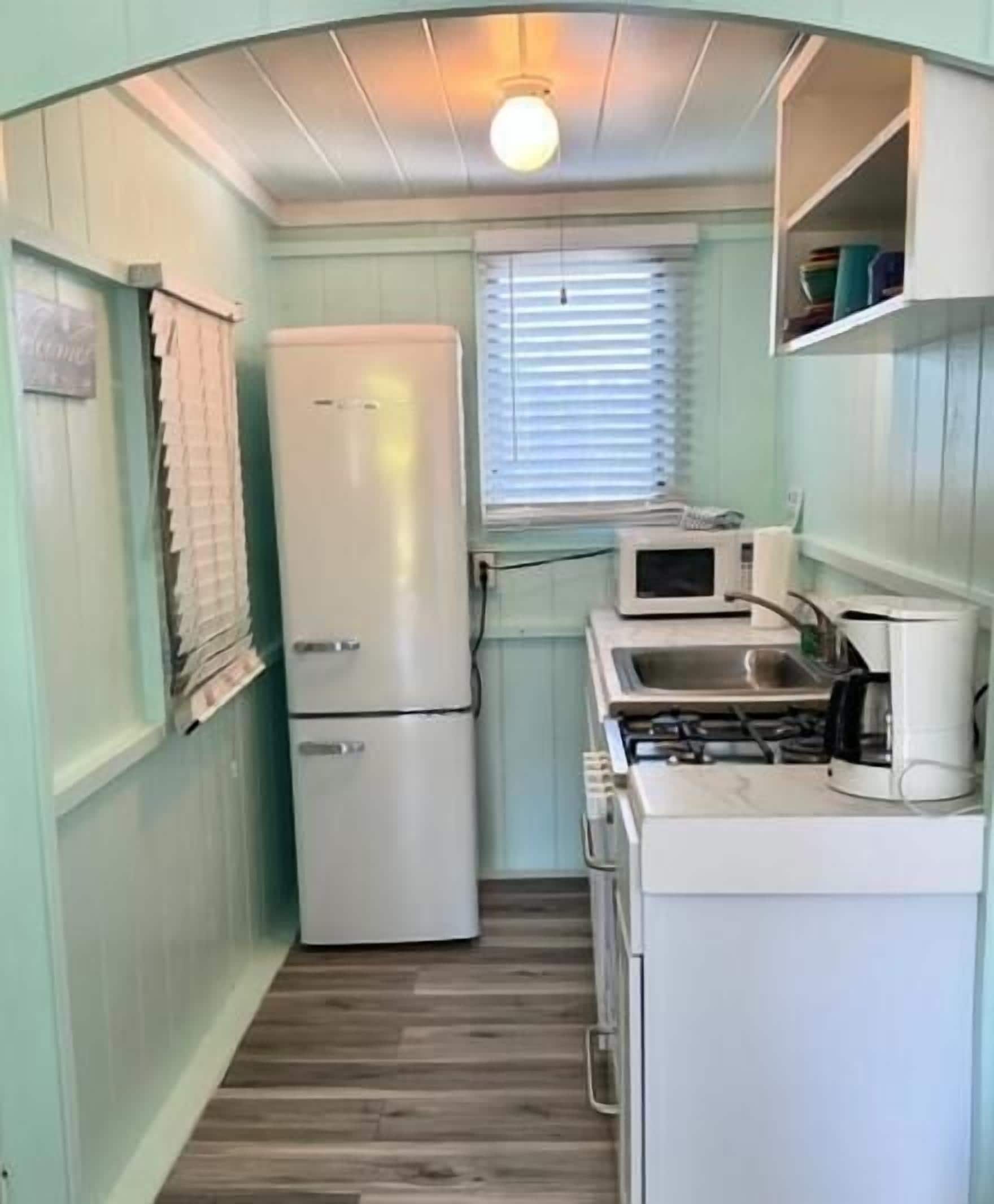 A compact kitchen with a refrigerator, microwave, and stove.