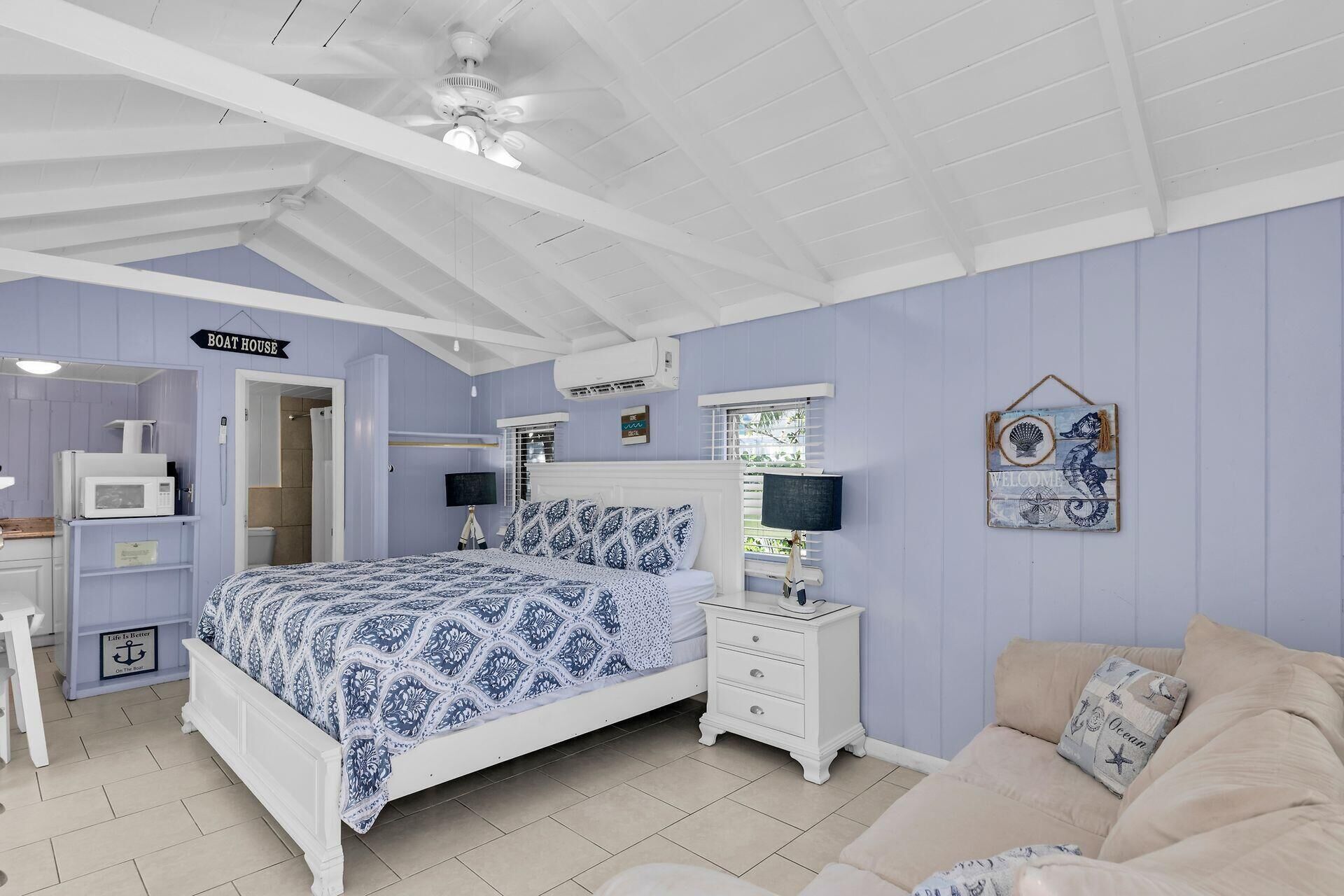 A bedroom with a bed, a nightstand, a dresser, a chair, and a sign that reads "Boat House".