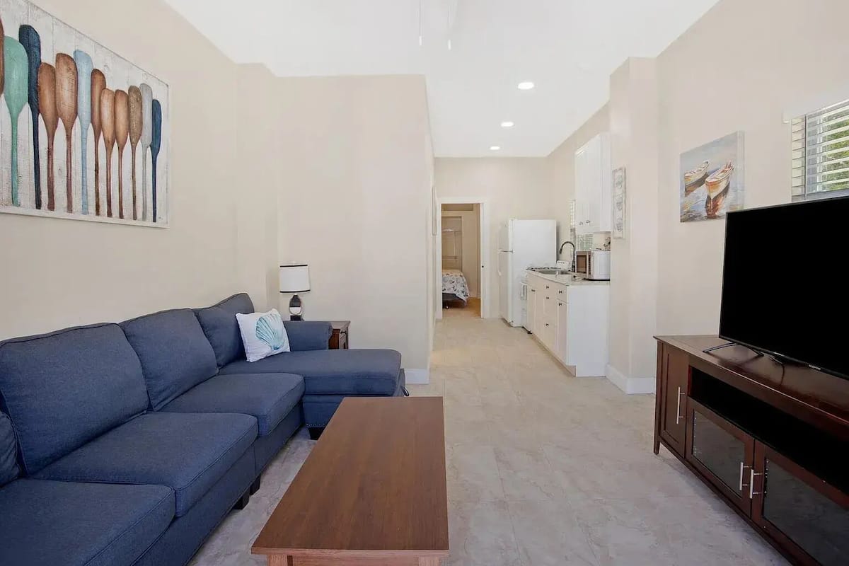 A living room with a sofa, coffee table, TV, and artwork.