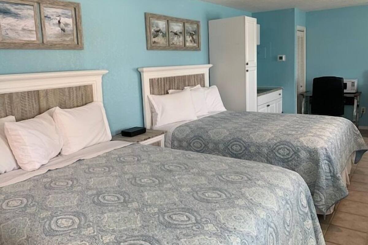 A hotel room with two beds, a desk, and a chair.