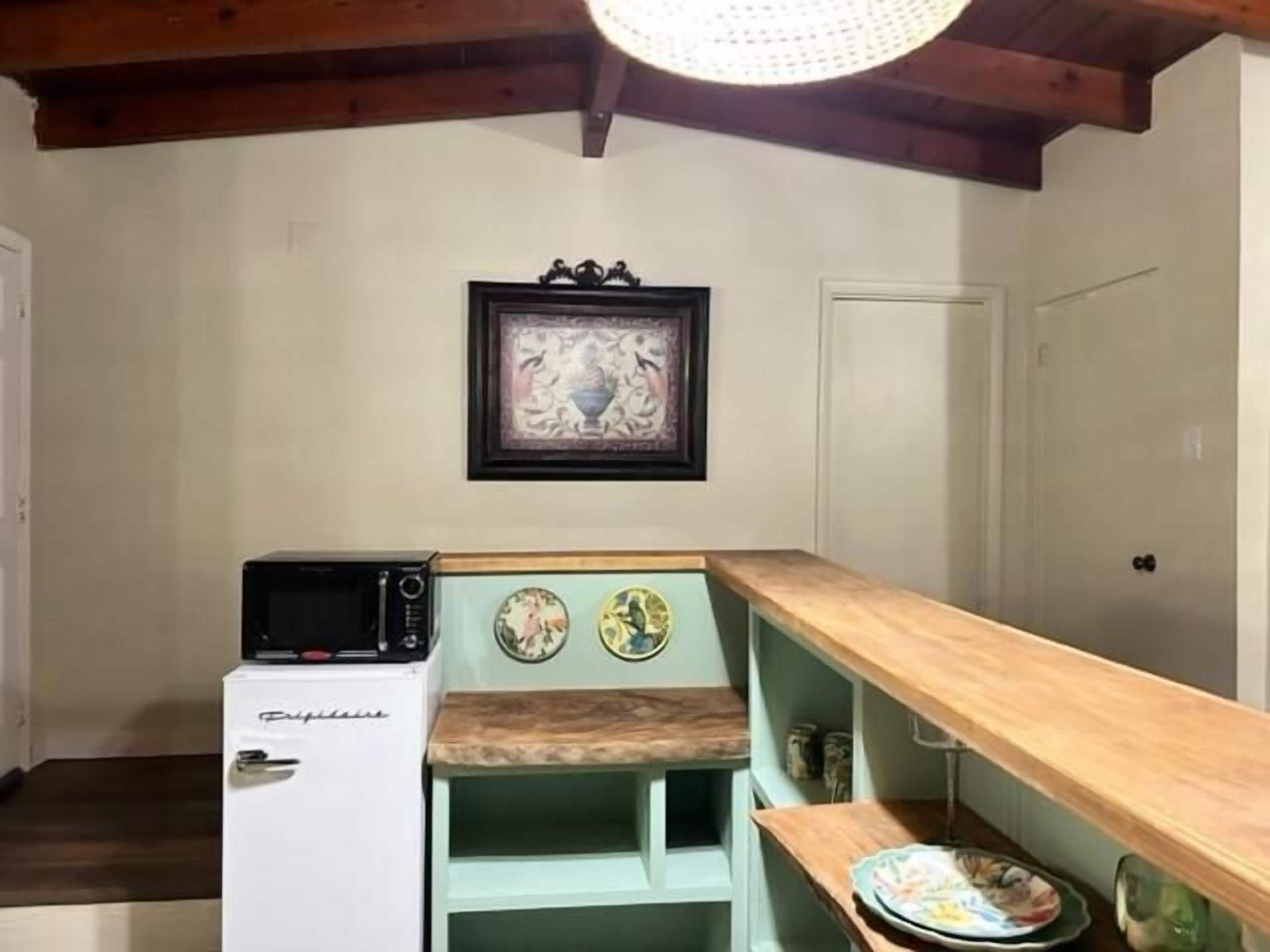 Cocina compacta con refrigerador, microondas y encimera de madera.