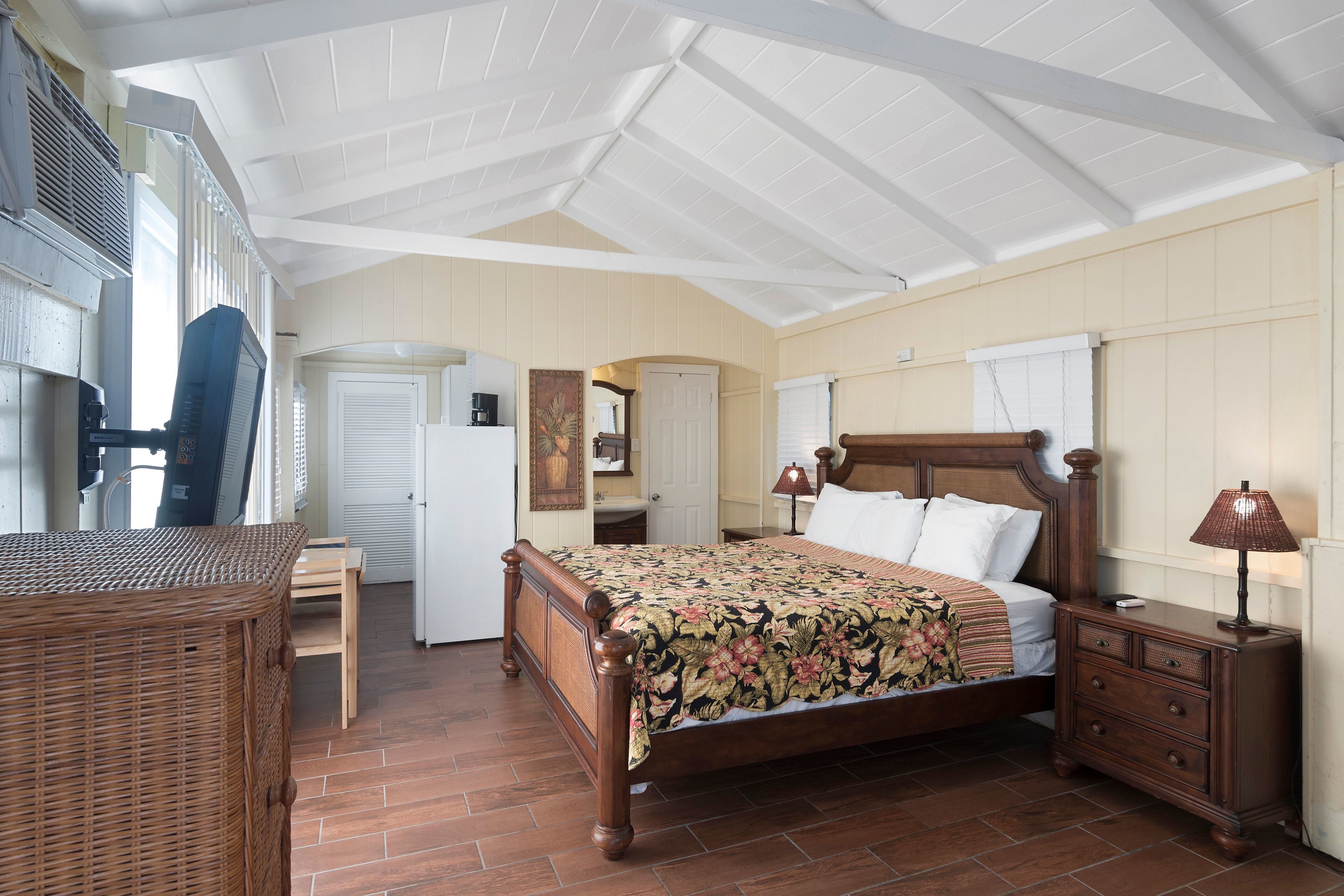 Une chambre à coucher avec un lit en bois, une table de chevet, une chaise en osier, un bureau et une armoire.