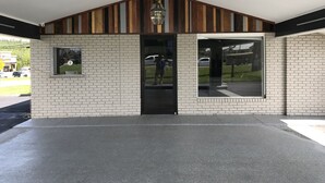A building with a brick facade, a large glass door, and a wooden slatted roof. - Rodeway Inn Calhoun South (Calhoun)