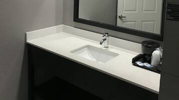 Een badkamer met een wit wastafel, een spiegel en een deur.