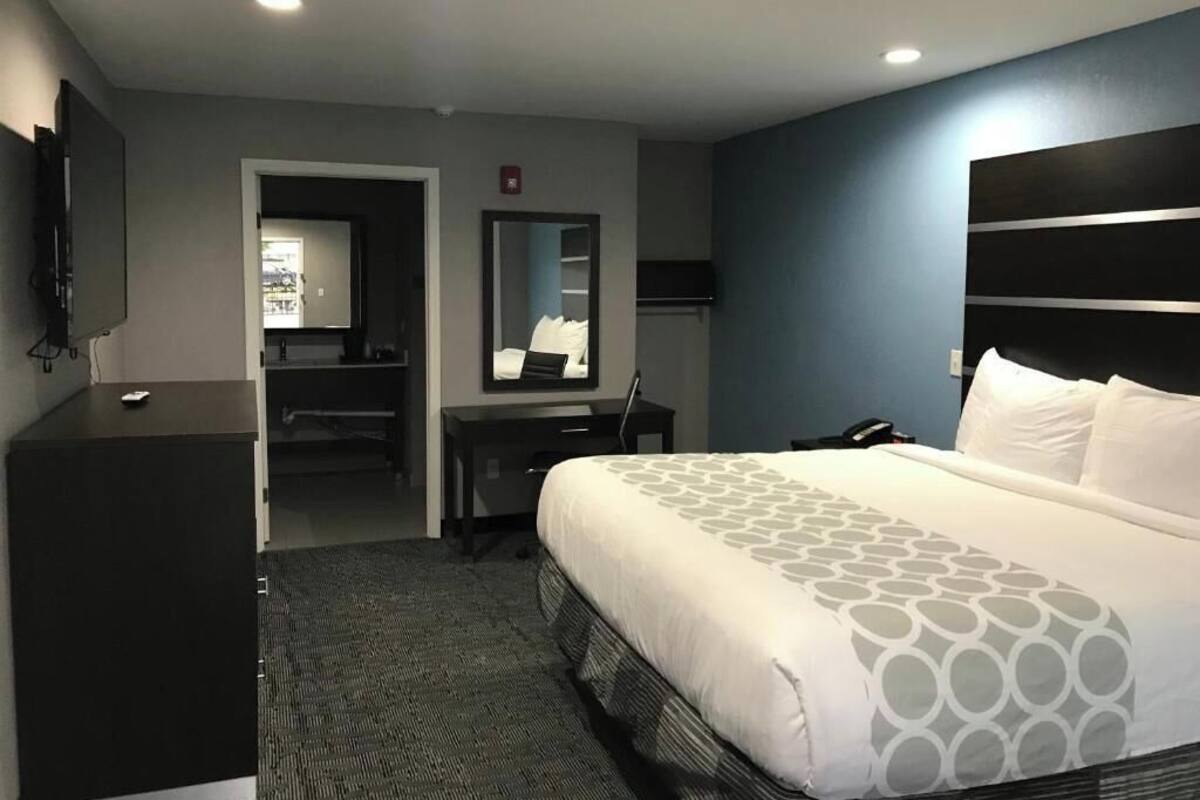 A hotel room with a bed, a desk, a chair, a TV, and a wardrobe.