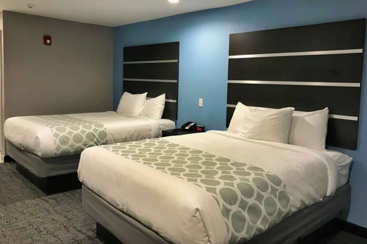 Two beds with headboards, a carpeted floor, and a wall-mounted phone.