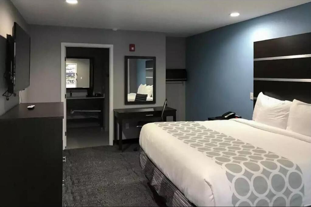 A hotel room with a large bed, a desk, a chair, a flat-screen TV, and a mirror.