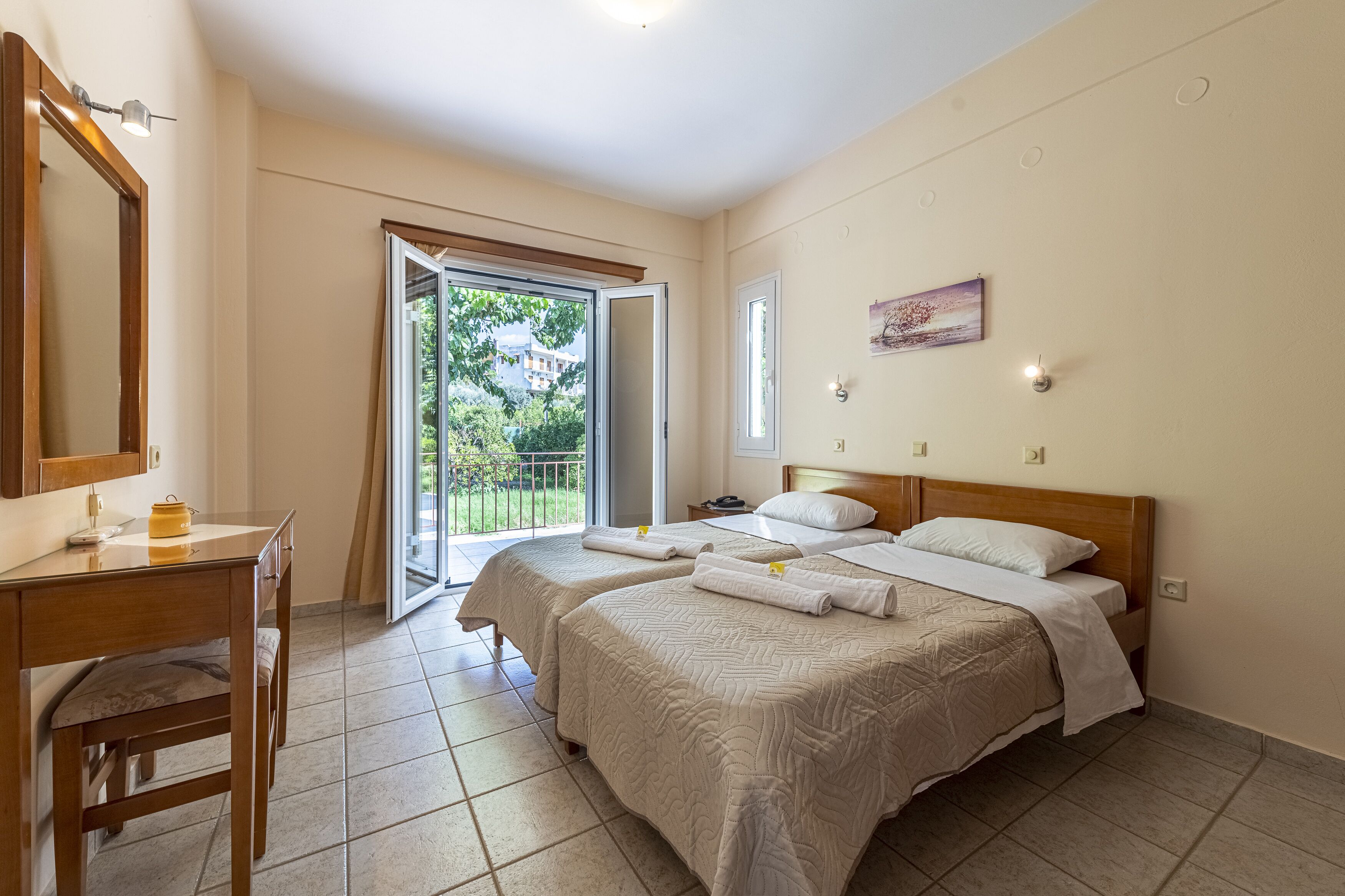 A hotel room with two beds, a desk, and a large window.