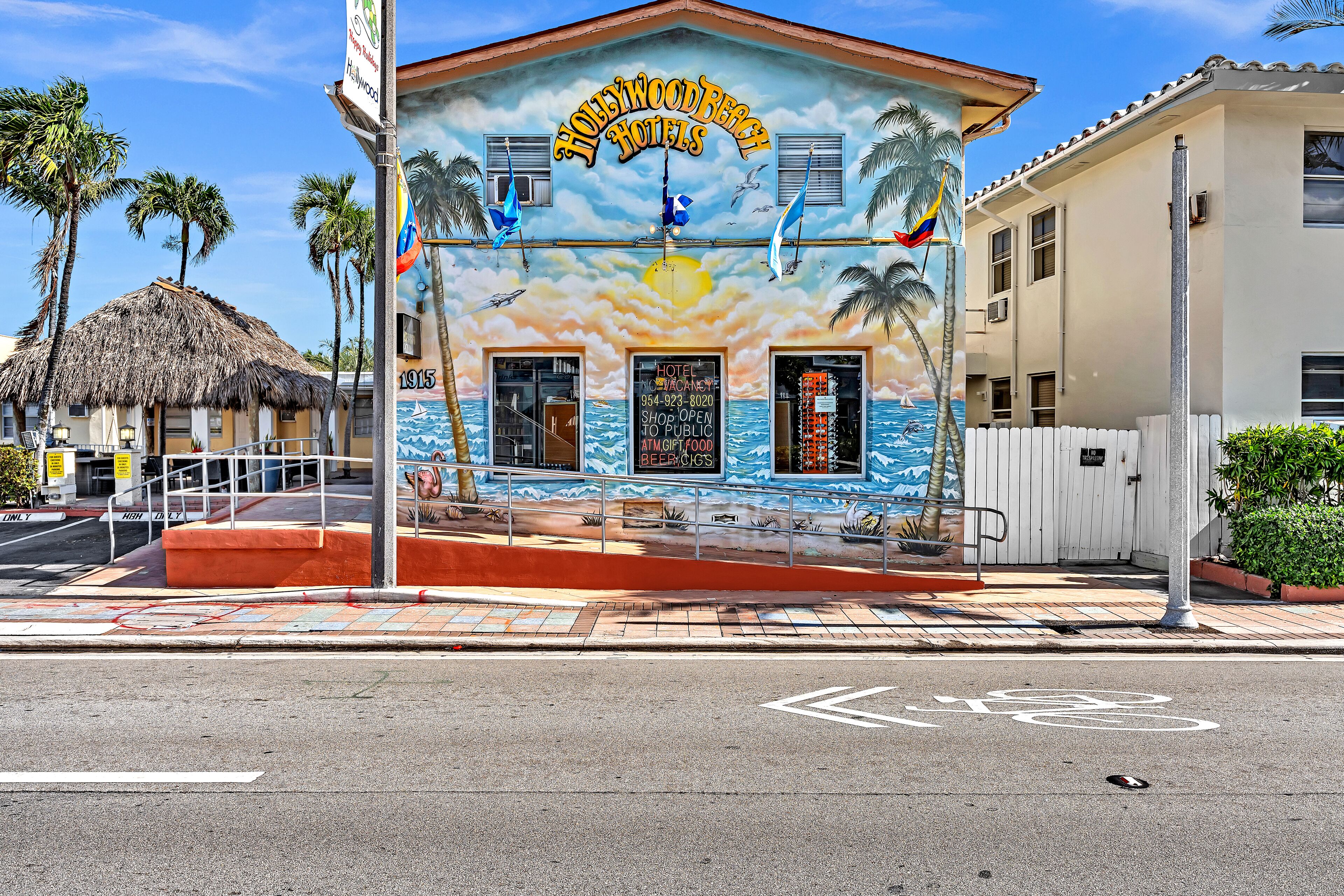 En byggnad med en väggmålning som föreställer en strandscen, en skylt för Hollywood Beach Hotels och en symbol för en cykelbana på vägen.