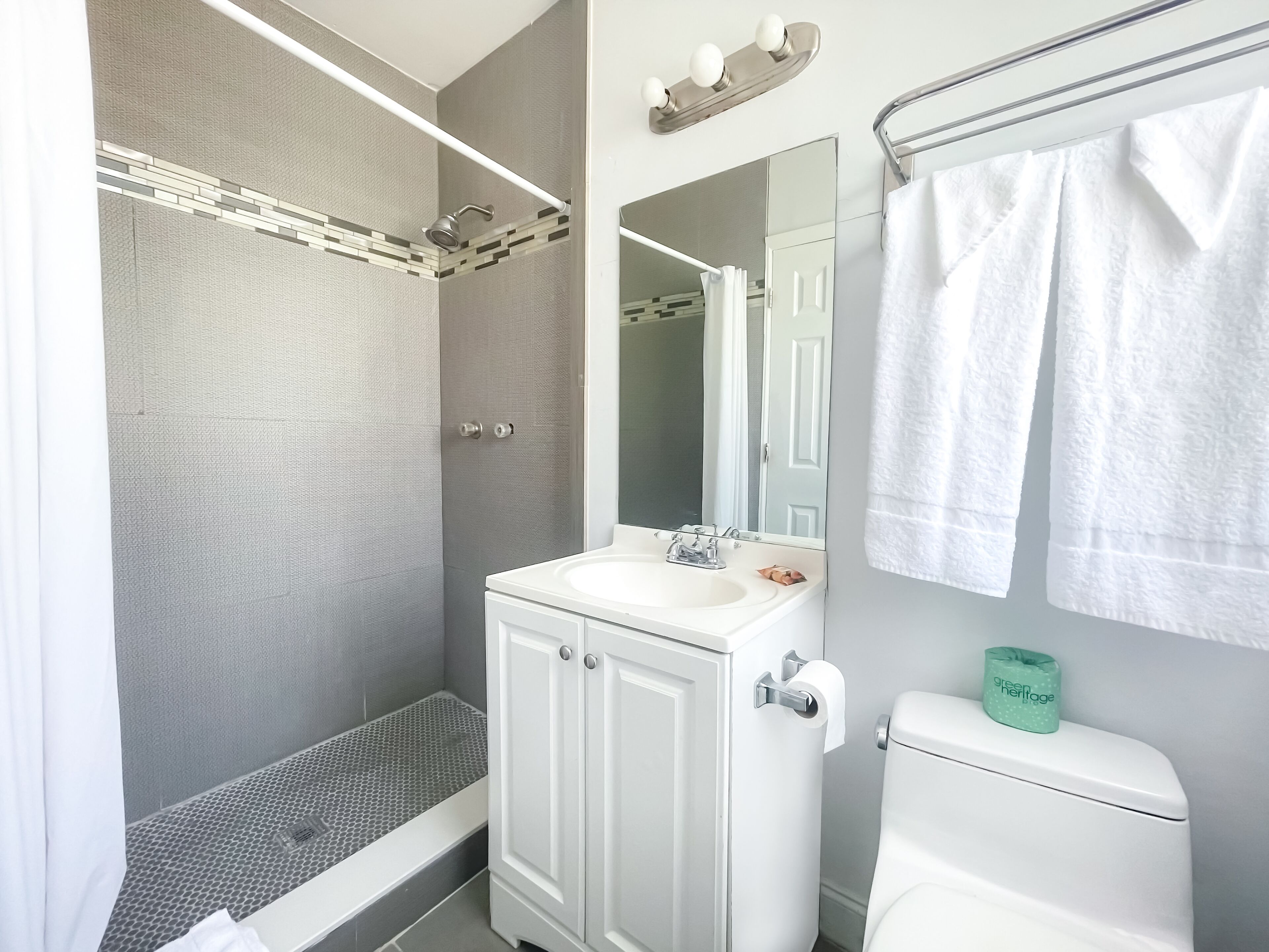 A bathroom with a shower, toilet, and sink.