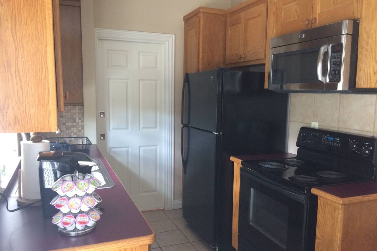 A kitchen with wooden cabinets, a black refrigerator, a microwave, and a stove.