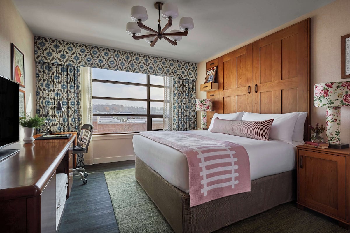 A bedroom with a large bed, wooden wardrobe, desk, and chair.