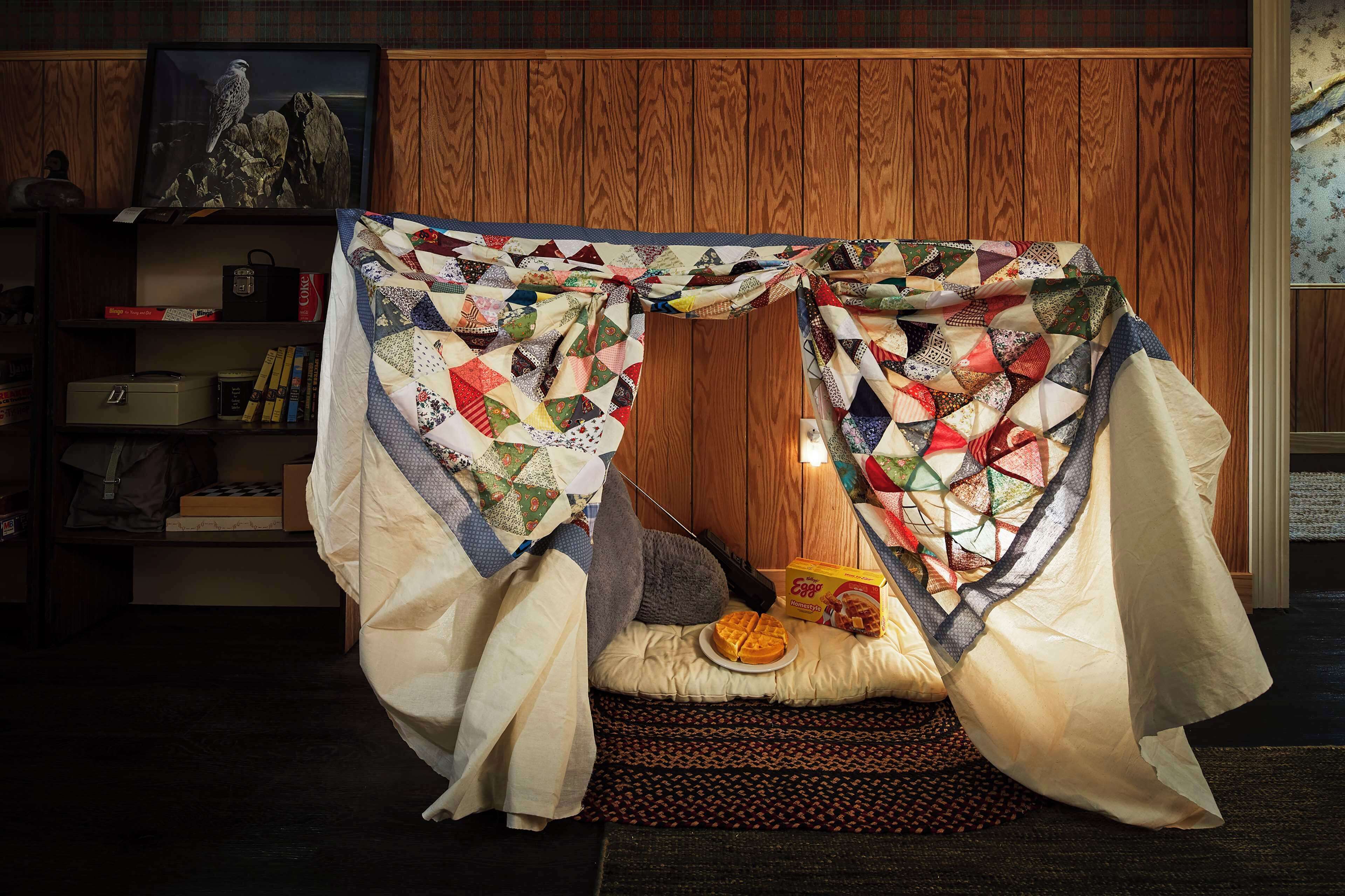Une chambre confortable avec un lit à baldaquin matelassé, une table de chevet avec une lampe et une bibliothèque contenant divers objets.
