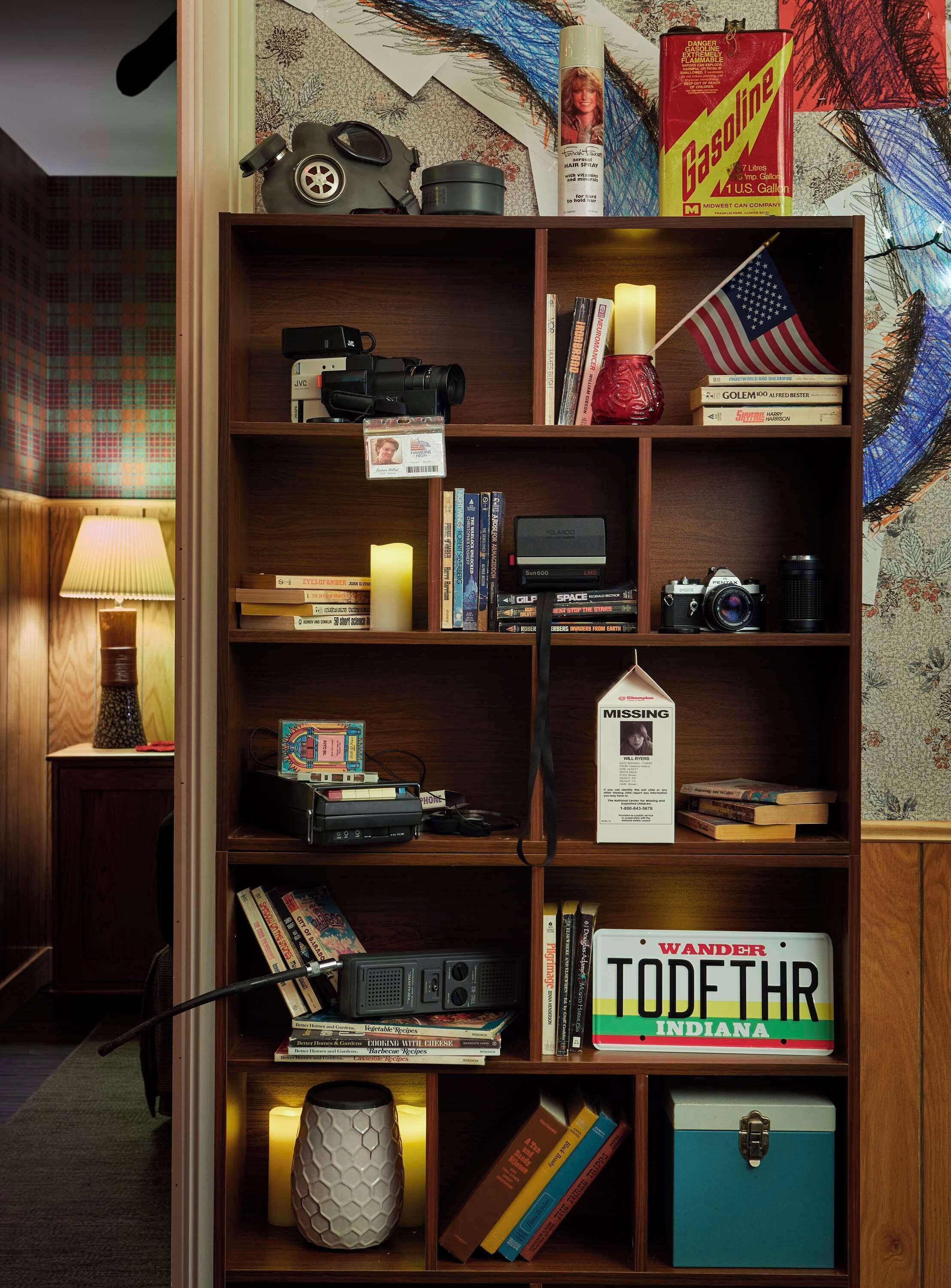 A bookshelf with various items including books, a camera, a gas can, and a candle.