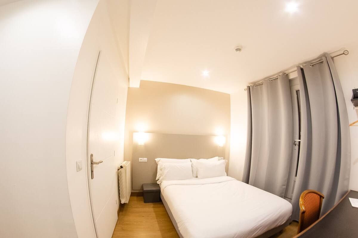 A modern hotel room with a large bed, a desk, and a chair.