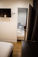 Una camera d'albergo con un letto, una TV a parete e un armadio.