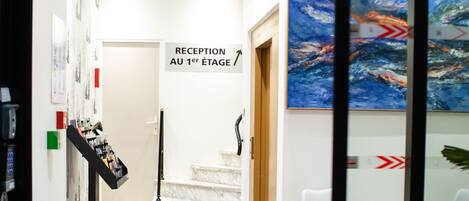 Un espace d’accueil avec un tapis bleu, un comptoir d’accueil et un escalier menant au premier étage.
