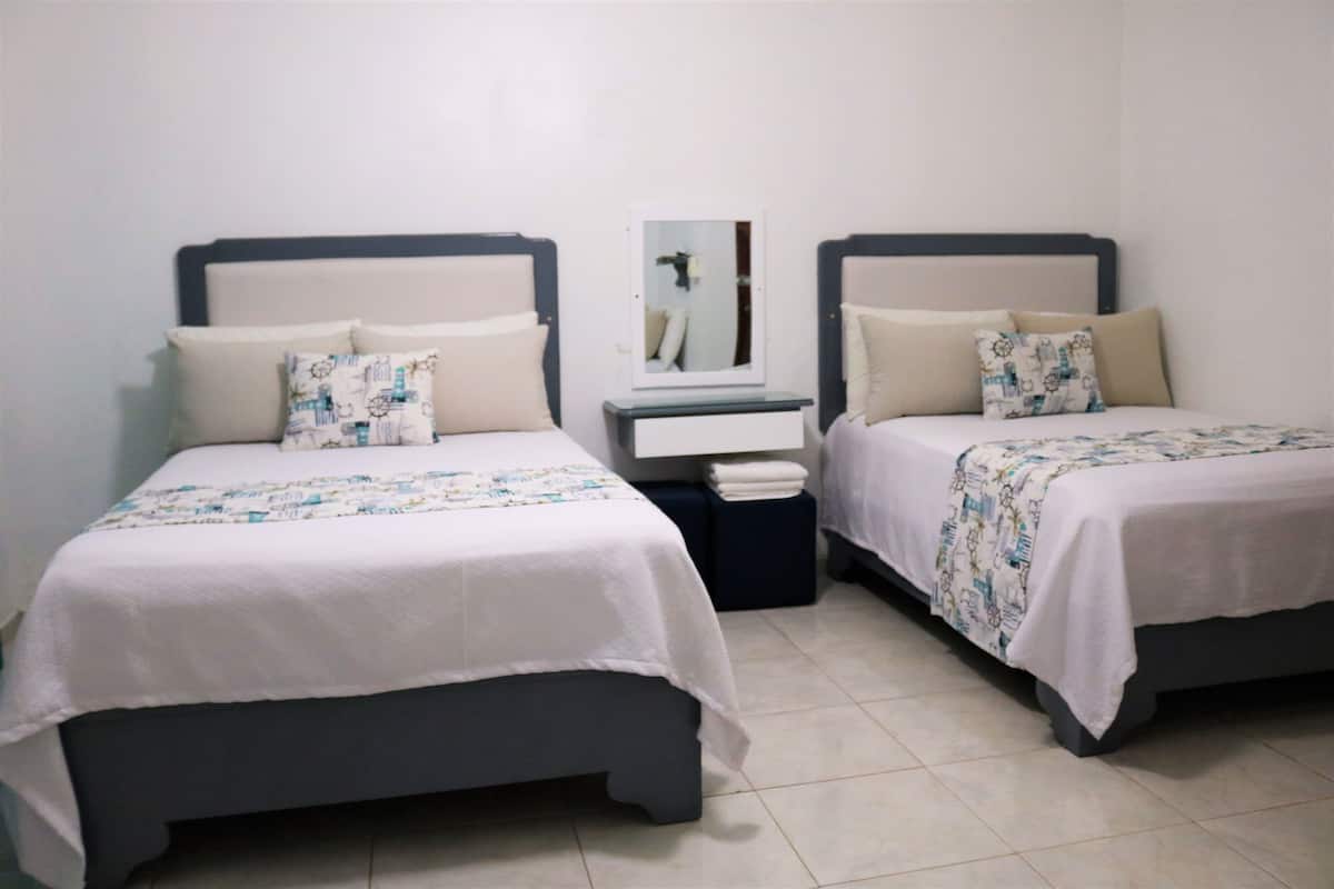 Two single beds with matching headboards and footboards, a bedside table with a mirror, and a small nightstand with a lamp.