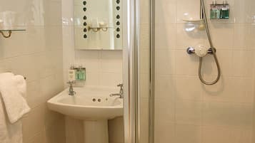 Baño con ducha de vidrio, lavamanos y espejo con detalles decorativos.