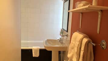 A bathroom with a white sink, a mirror, a bathtub, and a towel rack.