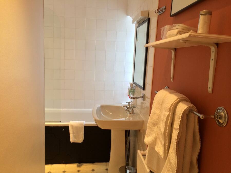 A bathroom with a white sink, a mirror, a bathtub, and a towel rack.
