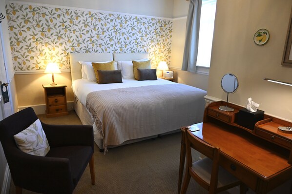 A neatly arranged bedroom with a bed, bedside tables, a desk, and a chair. - Orchard Club - Newton House (Knaresborough)