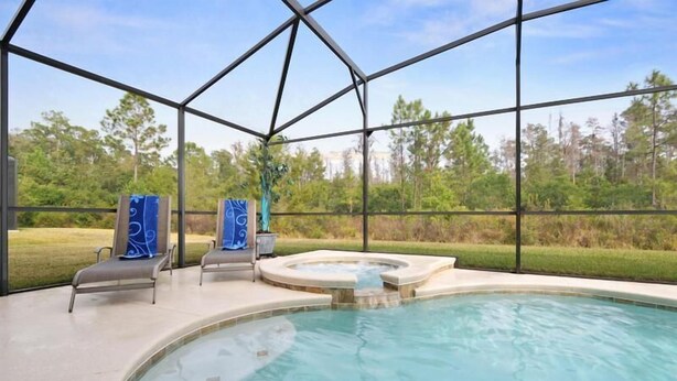 A pool area with a hot tub, lounge chairs, and a view of the surrounding landscape. - Calabria (Kissimmee)