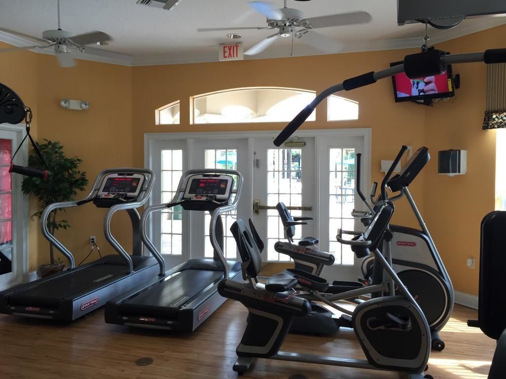 A gym with treadmills, elliptical machines, and a ceiling fan.