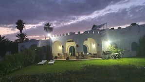 A courtyard with a white-walled building featuring arched doorways and a small pool area. - Maamoura Beach House (El Maâmoura)