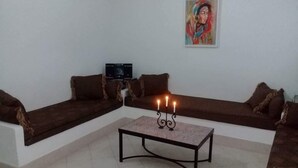 A living room with a brown sofa set, a small table with a candelabra, and a painting on the wall. - Maamoura Beach House (El Maâmoura)