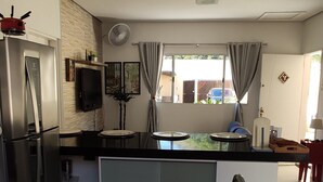 A modern kitchen with a refrigerator, stove, and sink. There are three potted plants on the counter. - Casa com piscina em Caraguatatuba (Caraguatatuba)