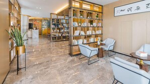 A modern lobby with marble flooring, a reception desk, and a large bookshelf filled with books. - Bantian Zhongcheng Atour Hotel (Shenzhen)