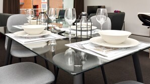 A dining table set with white plates, bowls, and wine glasses, with a candle holder and menu on the table. - Armagh Apartment 3 - Central Christchurch (Christchurch)