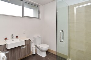 Ein modernes Badezimmer mit Duschkabine aus Glas, einem weißen Waschbecken und einer Toilette.
